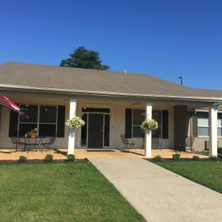A suburban house with a porch and well-maintained lawn under a clear blue sky.