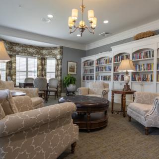A cozy living room with comfortable seating, bookshelves, and elegant lighting.