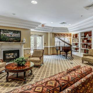 A cozy living room with a grand piano, fireplace, and bookshelves.