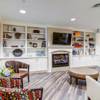 A modern living room featuring a fireplace, built-in shelves with decorative items, and a cozy seating area.