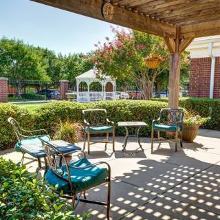 A cozy patio area with outdoor seating and a view of a garden gazebo.