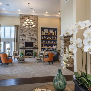 A spacious and elegantly decorated living room featuring a stone fireplace, comfortable seating, and modern decor accents.
