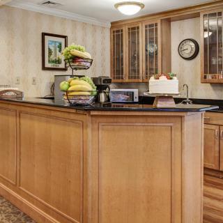 A cozy kitchen with wooden cabinetry, featuring a countertop adorned with a fruit basket and a cake.