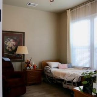 A cozy bedroom with a single bed, armchair, and a lamp by the window.