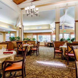 An elegant restaurant dining area with neatly arranged tables and chairs, featuring a chandelier and tasteful decor.