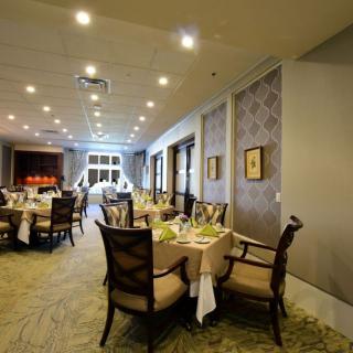 A spacious and elegantly decorated dining room with multiple tables set for a formal meal.