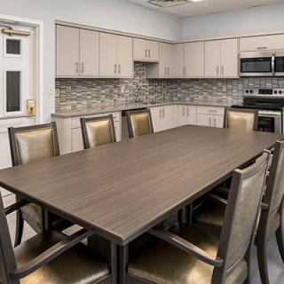A modern conference room featuring a large meeting table and adjacent kitchen area.