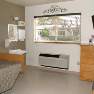 A cozy bedroom with a bed, dresser, and a window overlooking the outside.