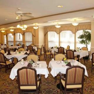An elegant dining room with neatly arranged tables and chairs, well-lit by overhead lamps, creating a cozy atmosphere.