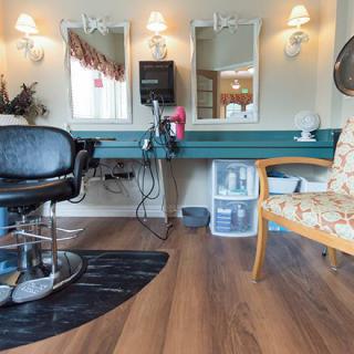An interior view of a cozy salon with a hairdressing chair, mirrors, and styling equipment.