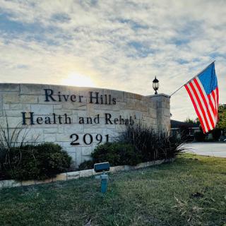 Entrance sign for River Hills Health and Rehab, featuring an American flag.