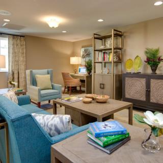 A cozy and elegantly designed living room featuring comfortable seating, a coffee table, and well-organized bookshelves.