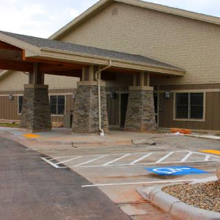 A modern building entrance with stone accents and a parking area.