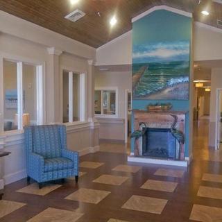 A spacious lobby area featuring a comfortable blue armchair, mural art, and classic architectural design.