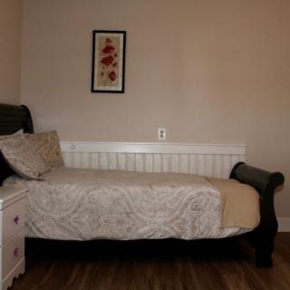 A cozy bedroom with a single bed, nightstand, and wall art.