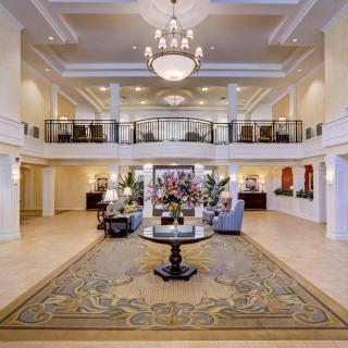 A luxurious hotel lobby featuring elegant decor, a prominent chandelier, and comfortable seating areas.
