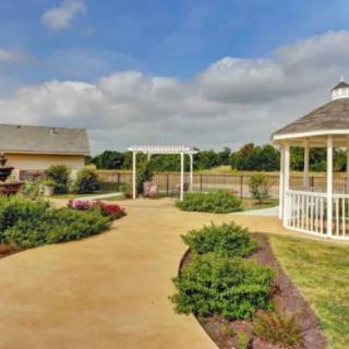 A well-maintained garden with a gazebo and a pathway under a cloudy sky.