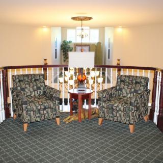 Cozy lounge area with patterned armchairs and a central table in a well-lit room.
