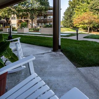 A peaceful porch with white chairs overlooking a green garden and pathway.