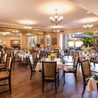 An elegant dining room with neatly arranged tables and chairs, adorned with chandeliers.