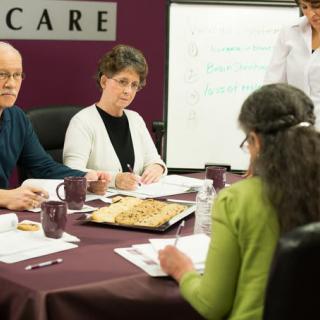 A group of people engaged in a business meeting around a conference table.