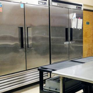 A commercial kitchen with large stainless steel refrigerators and a preparation table.