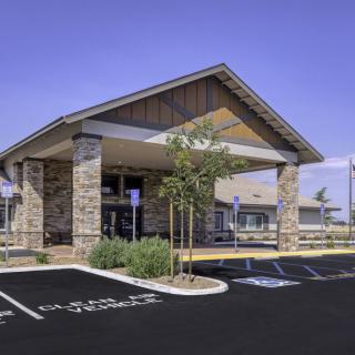Modern building with a stone facade and a parking lot in front.