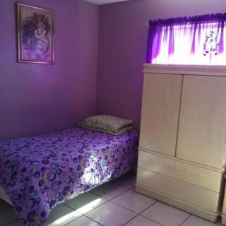 A small bedroom with a single bed and purple decor.