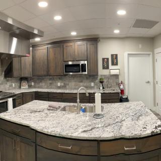 A modern kitchen interior featuring a granite island with stainless steel appliances and wooden cabinets.