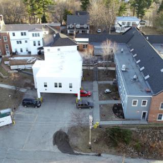 Aerial view of a residential area featuring a mix of buildings and a parking lot surrounded by trees.