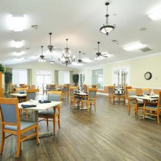 A spacious dining room with wooden tables and chairs, illuminated by elegant chandeliers.
