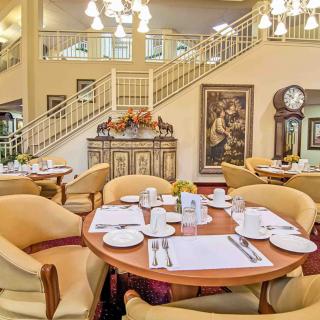 An elegant dining area with neatly set tables, classic decor, and a grand staircase.