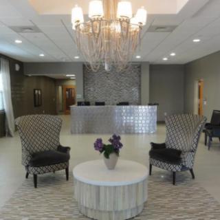 A modern and elegant lobby with a chandelier, reception desk, and comfortable seating.