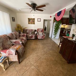 A cozy living room with patterned sofas, a ceiling fan, and patriotic decorations.