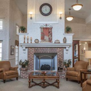 A cozy living room featuring a central brick fireplace surrounded by leather chairs.