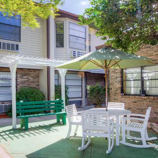A cozy outdoor patio area with a table, chairs, and an umbrella next to a building.