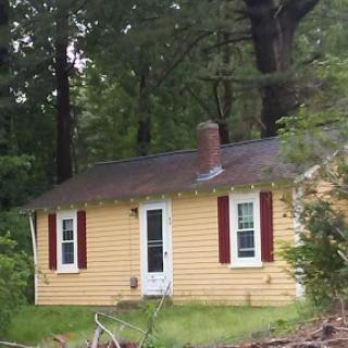 A charming yellow cottage nestled in a wooded area.
