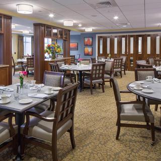 A well-appointed dining room with neatly arranged tables and chairs in a formal setting.
