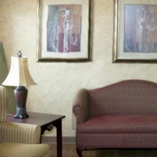 A cozy living room with a sofa, table lamp, and framed artwork on the wall.