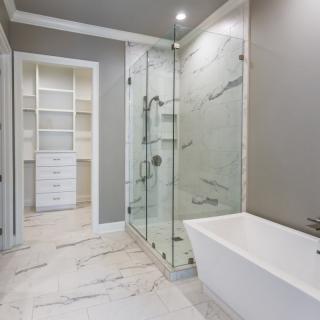 A modern bathroom featuring a glass-enclosed shower, standalone bathtub, and adjacent walk-in closet.
