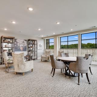 A spacious and elegantly decorated living room with large windows, featuring comfortable seating and a central table.