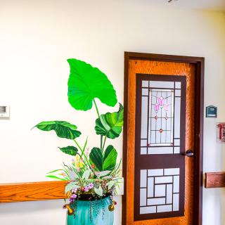 A hallway with a potted plant beside a decorative door.