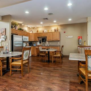 A cozy kitchen and dining area with wooden floors, tables, and chairs, featuring modern appliances and cabinets.