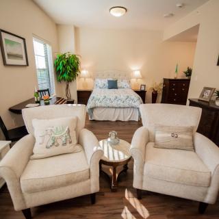 A cozy bedroom with two armchairs, a bed, and elegant decor.