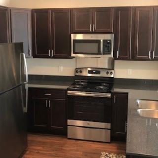 Modern kitchen with stainless steel appliances and dark cabinets.