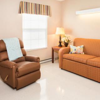 A cozy living room featuring a comfortable sofa, a reclining chair, and warm lighting.