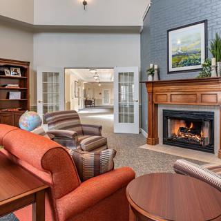 A cozy living room featuring a fireplace, comfortable armchairs, and wooden shelves.