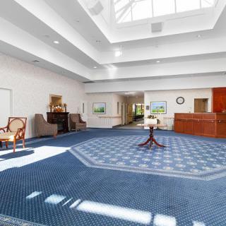A spacious lobby with a carpeted floor, seating areas, and a reception desk.