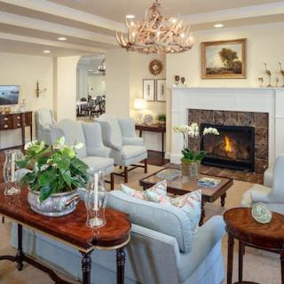 A cozy traditional living room with a chandelier, fireplace, and elegant seating area.
