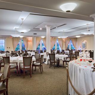 A formal dining hall set up with round tables and chairs, ready for an event.